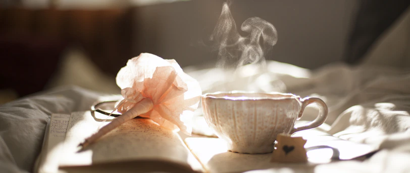 teacup on book beside pink flower decor