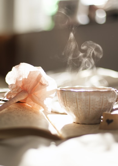 teacup on book beside pink flower decor