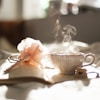 teacup on book beside pink flower decor