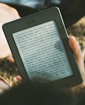 A peaceful scene of a person reading an e-book outdoors on a sunny day.