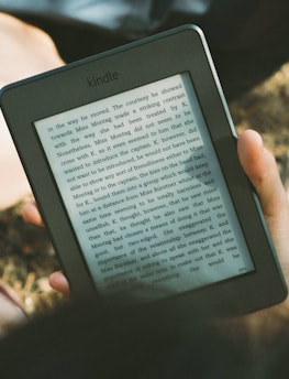 A peaceful scene of a person reading an e-book outdoors on a sunny day.