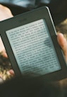 person holding black Amazon Kindle e-book reader