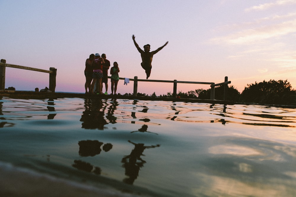 man jump in mid air on body of water