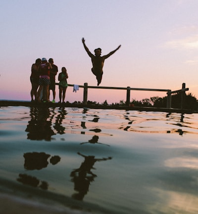 man jump in mid air on body of water