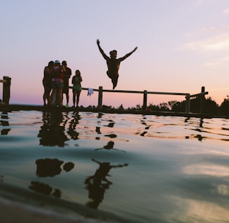 man jump in mid air on body of water