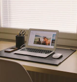 A minimalist workspace featuring matte black leather office accessories arranged neatly on a wooden desk.