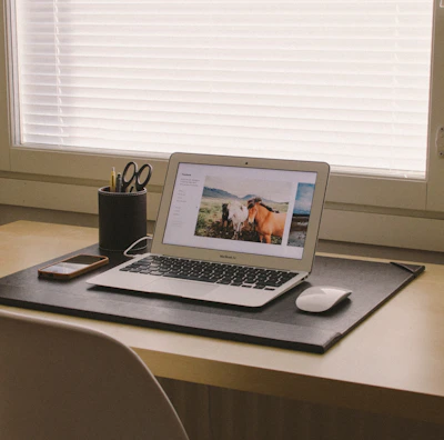 A minimalist workspace featuring matte black leather office accessories arranged neatly on a wooden desk.