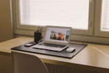 A minimalist workspace featuring matte black leather office accessories arranged neatly on a wooden desk.