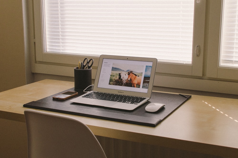 allumé MacBook sur un bureau en bois beige