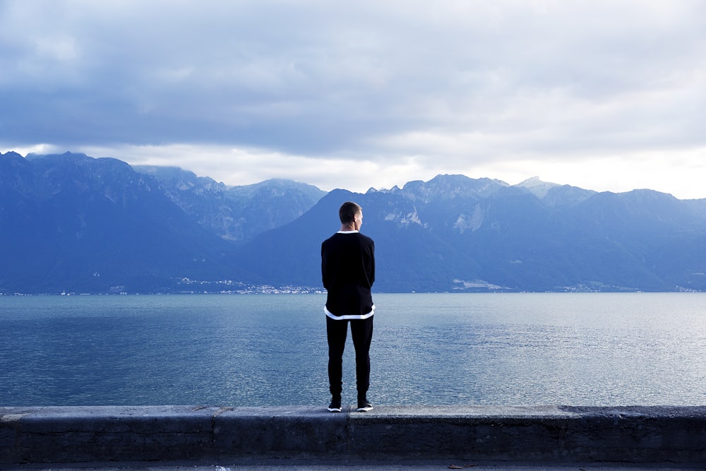 persona che indossa pantaloni neri e top in piedi sul muro