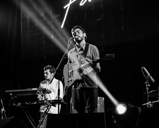 grayscale photography of men performing on stage