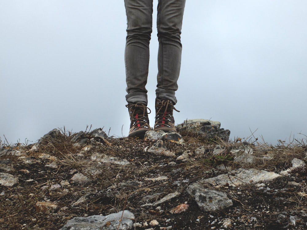 person in gray jeans standing on rocks during daytime