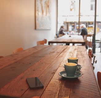 two gray ceramic mugs on brown wooden dining table