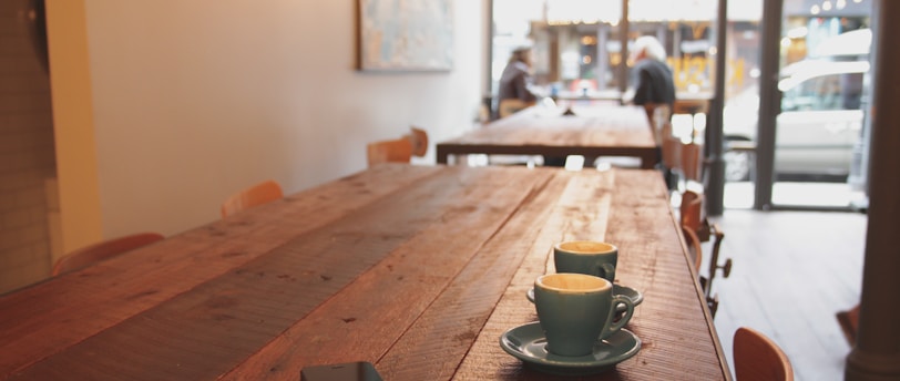 two gray ceramic mugs on brown wooden dining table
