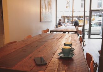 two gray ceramic mugs on brown wooden dining table
