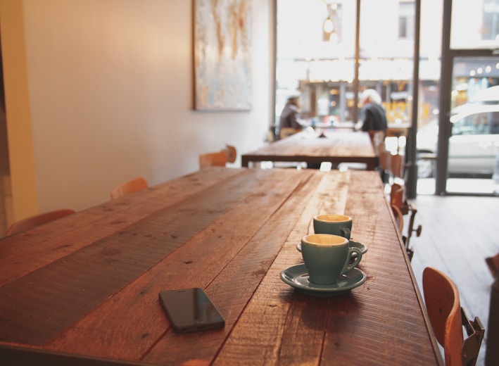 two gray ceramic mugs on brown wooden dining table
