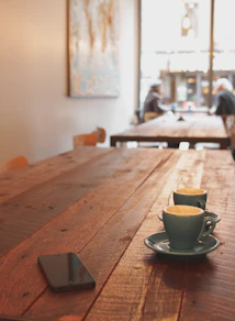 two gray ceramic mugs on brown wooden dining table