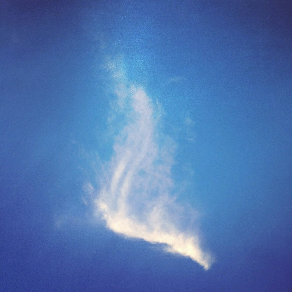 a plane flying through a blue sky with clouds