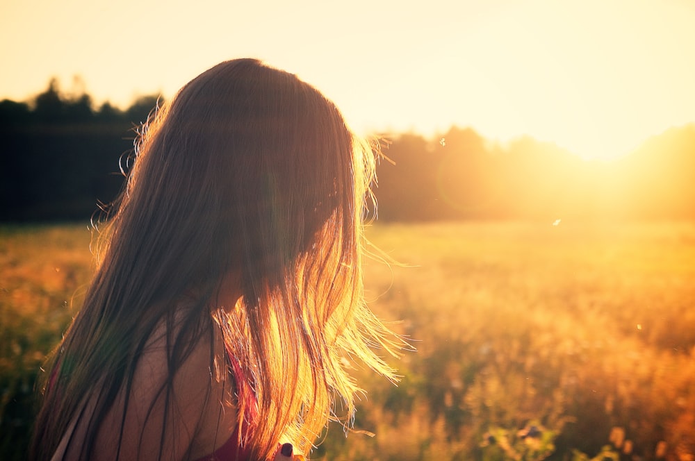 woman wearing black camisole top walking on grass field during sunrise