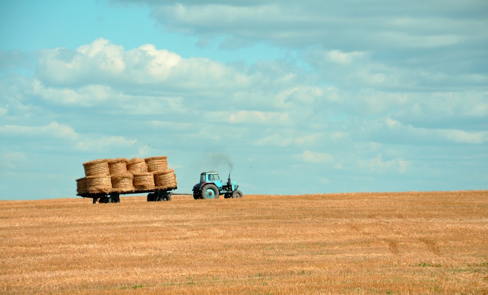 Braunes Heu auf dem Traktor unter weißem und blauem Himmel während des Tages