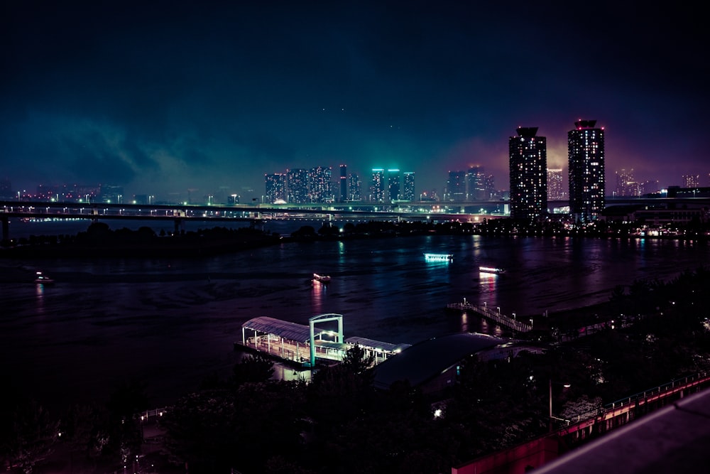 bridge above body of water near lightened buildings during night time