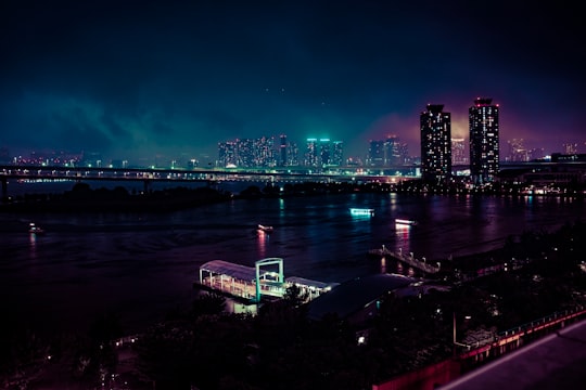 bridge above body of water near lightened buildings during night time in Odaiba Japan