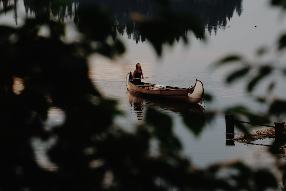 Mujer con top negro de tirantes finos sentada en canoa marrón