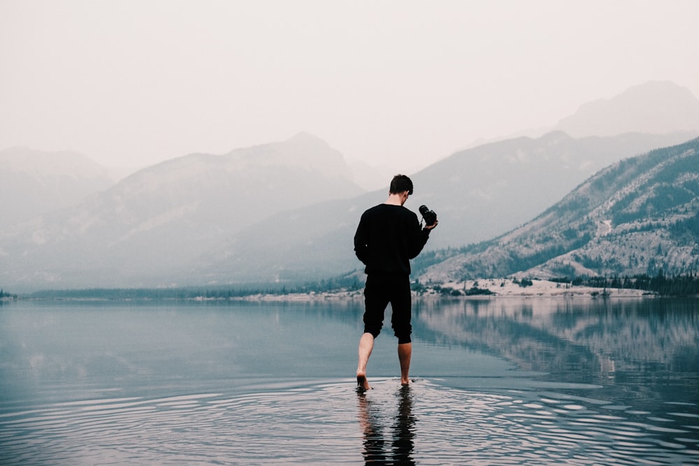 man in black shirt and black capri outfit on body of water during foggy weather