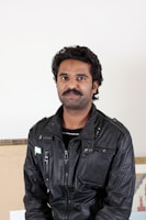 A sleek black leather jacket displayed on a minimalist white background.