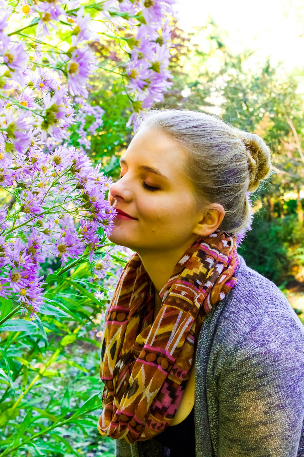 woman smelling purple petaled flowers