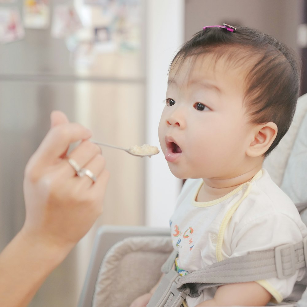 mom feeding baby in a high chair baby safe food and drinks