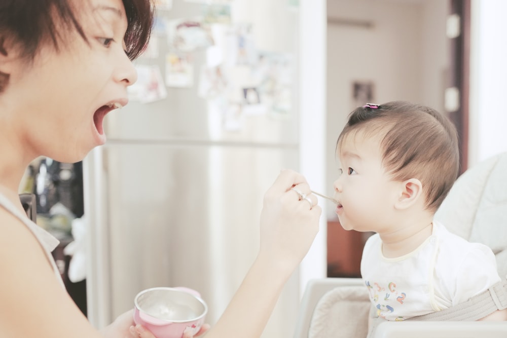 mother feeds the baby using small spoon