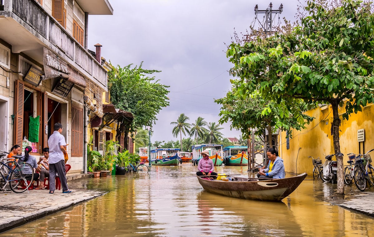 Hoi An October — two women navigate flooded Ancient Town streets by boat as the Thu Bon River inundates the historic lanes