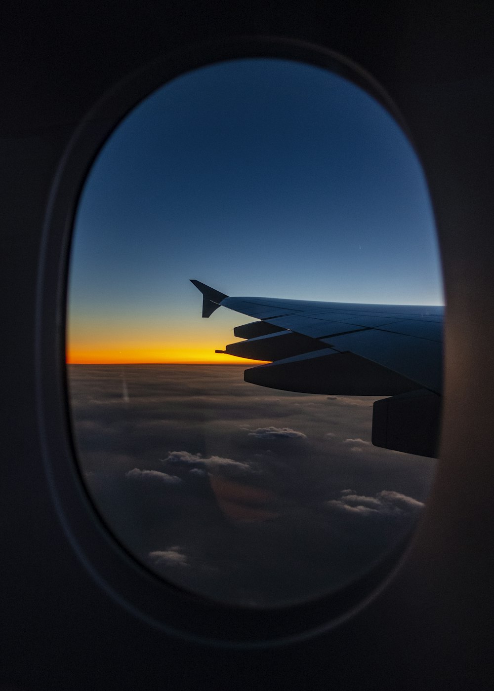 airplane window overlooking clouds during golden hour