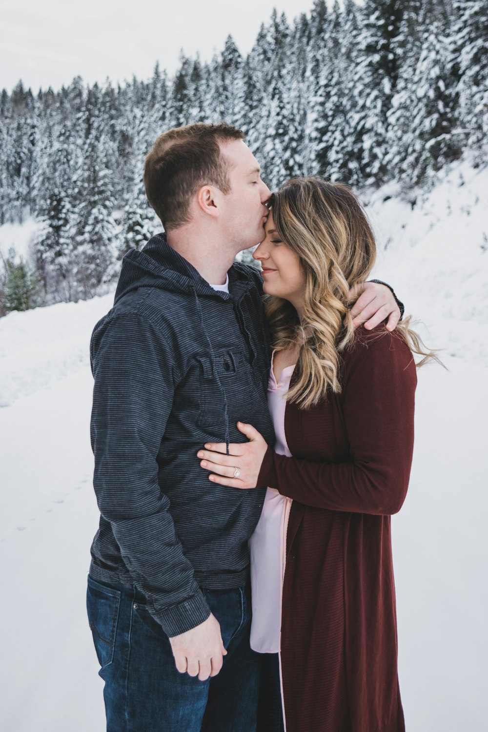 man kissing woman's forehead