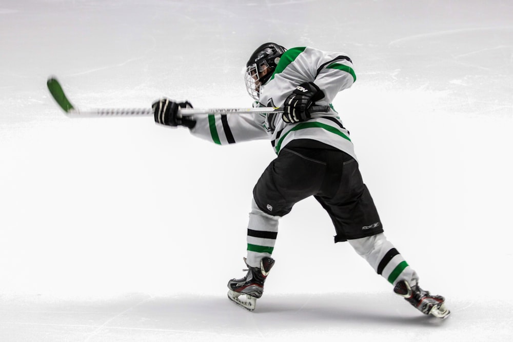 homme portant un maillot de hockey sur glace vert et blanc tout en jouant