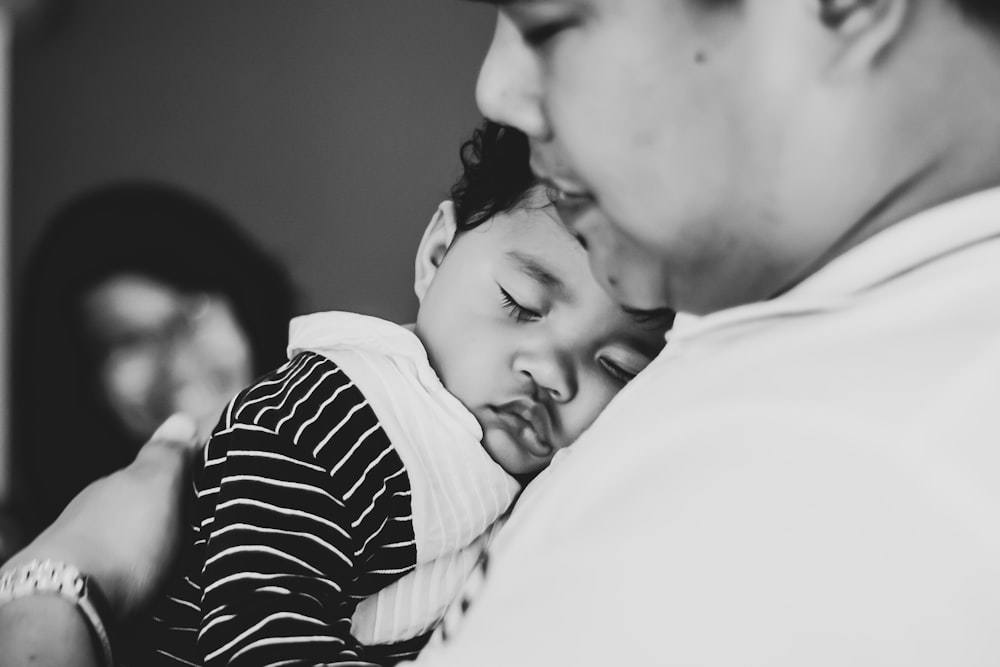 grayscale photo of man carrying child