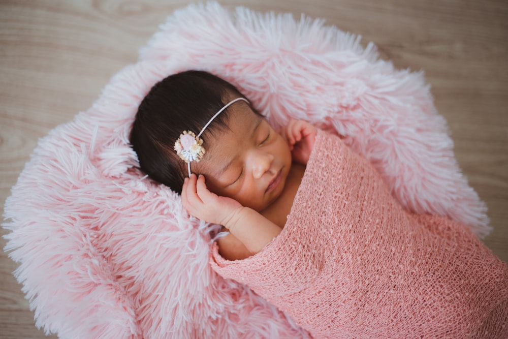 ピンクの毛皮のパッドで寝ている赤ちゃん