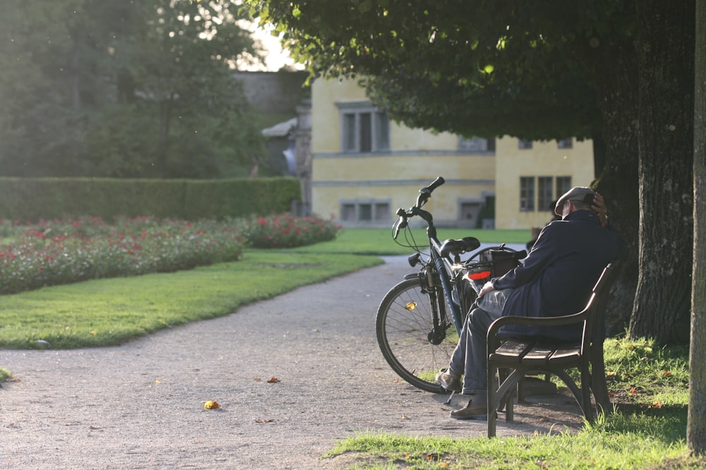 man sitting on bench beside bicycle