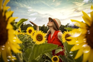 selective focus photography of woman blowing bubbles surrounded by sunflower field