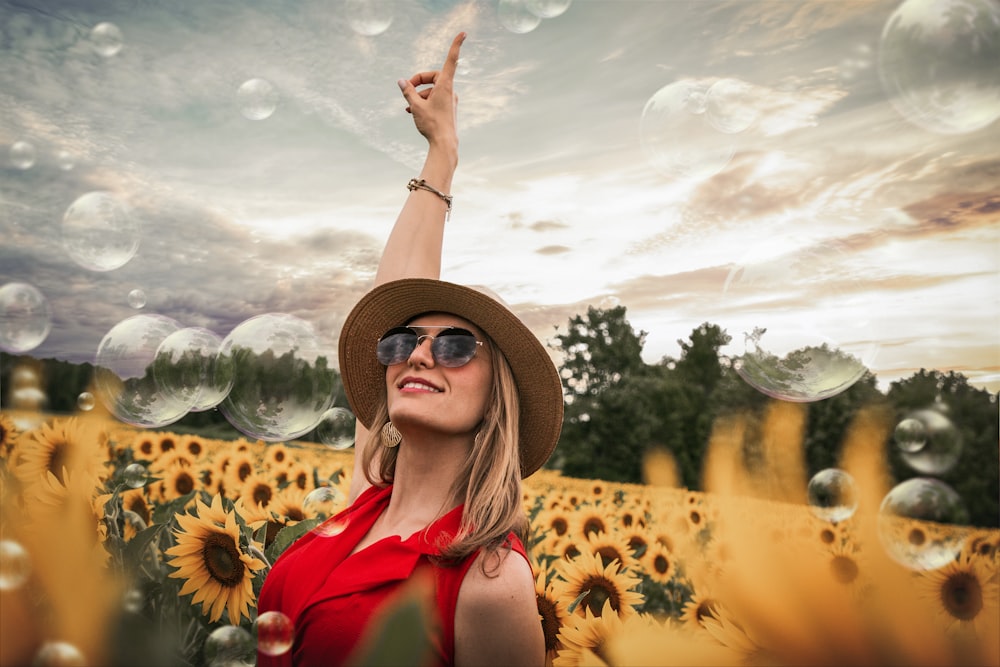 woman in red top lifting hand on middle of sunflower field