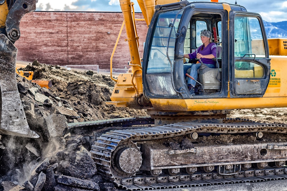 woman riding on yellow excavator at daytime