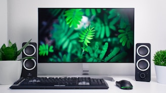 Muted green plant leaves gently framing a clean, minimalist desk setup with a focus on clarity and simplicity.