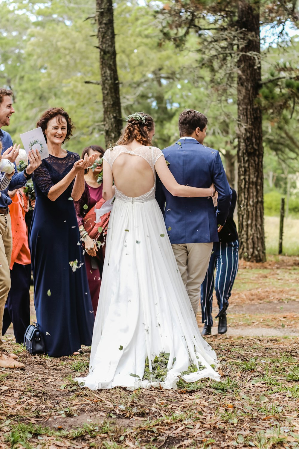 newly wed walking in front of crowd in middle of woods