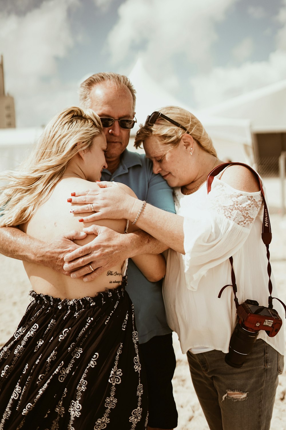 man hugging woman beside woman during daytime