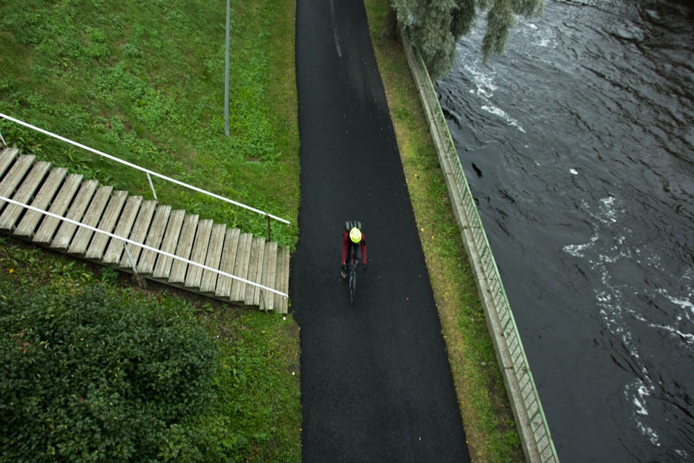 aerial photo of man cycling near body of water during daytime
