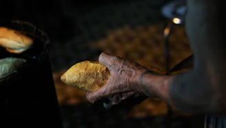 Warm earth-toned image of a hand holding freshly baked plant-based bread with a backdrop of a rustic kitchen