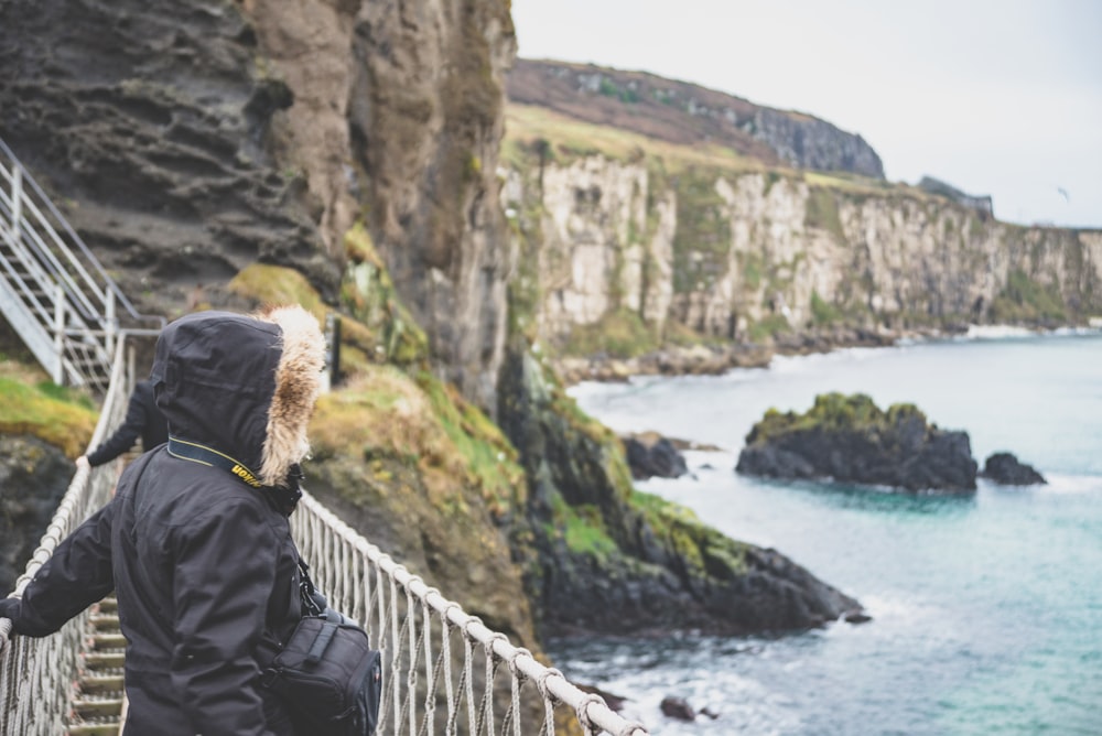 person standing on stairs near body of water