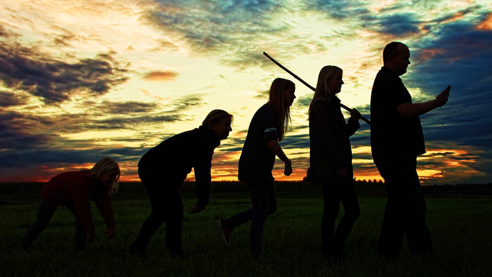 silhouette photo of group people standing on grass