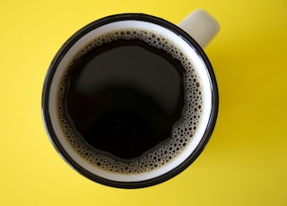 cup of black coffee on yellow surface